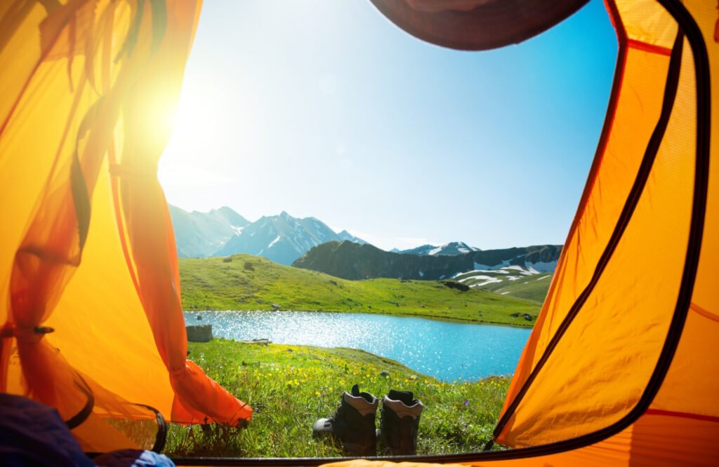 person sitter i telt med utsikt mot fjellet og havet