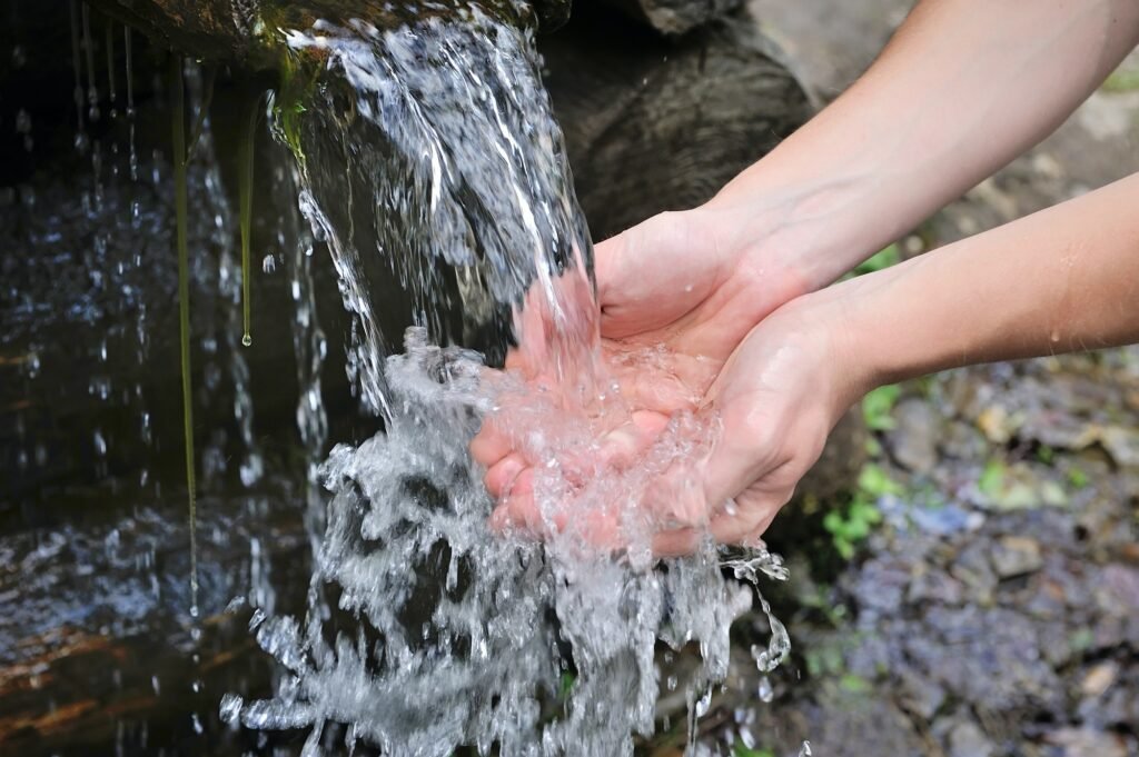 Drinking water and natural water in the hands.