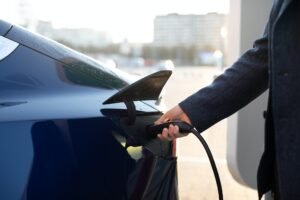Close-up of man's hand, inserting a charger into his electric car against the background of