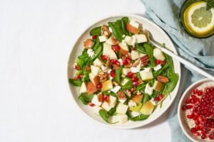 Fruits salad with nuts, balanced food, clean eating. Spinach with apples