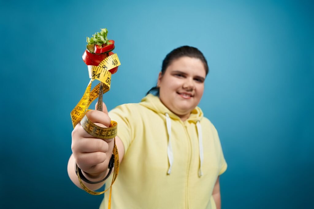 Fat girl holding fork with vegetables and measuring tape